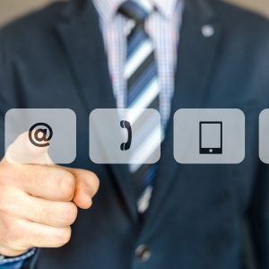 Hombre de negocios señalando iconos de contacto: email, teléfono y móvil.
