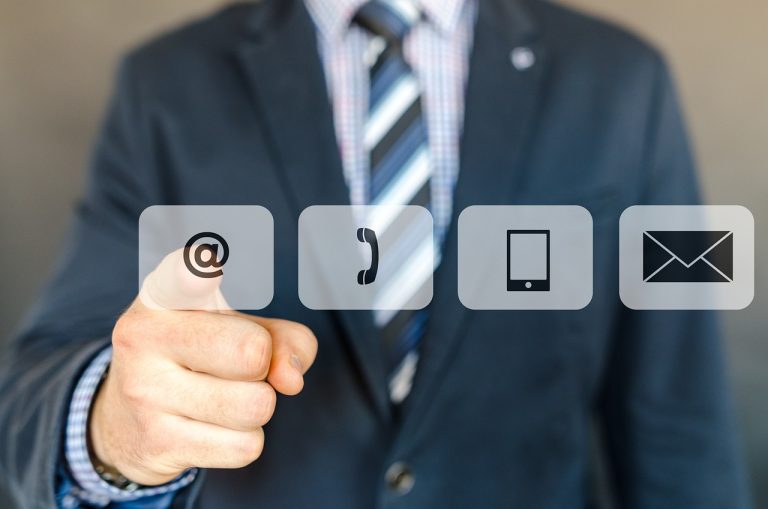 Hombre de negocios señalando iconos de contacto: email, teléfono y móvil.